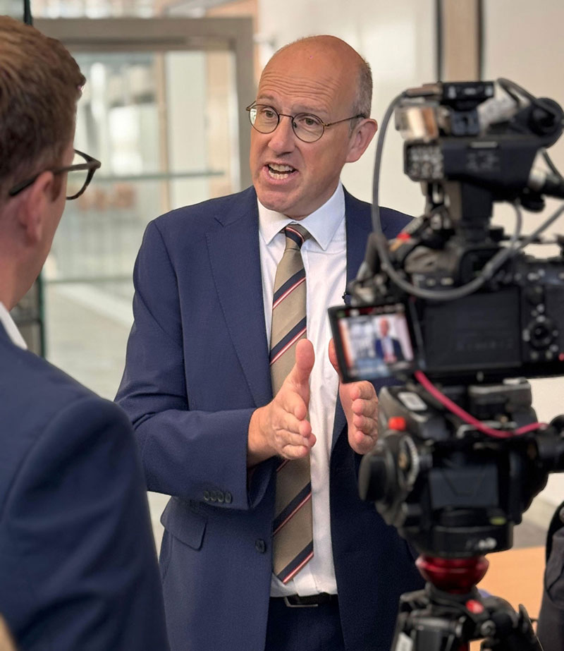 Dyn yn sgwrio gyda camera yn filmio